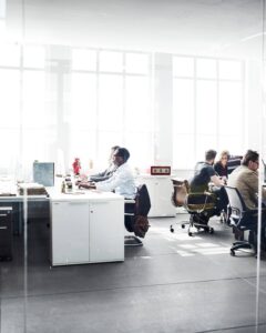 two groups of people working behind glass doors at two different sets of desks