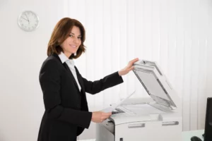 Businesswoman Copying Paper On Photocopy Machine | The Document Group | The Document Group Employee making copy for her meeting copying